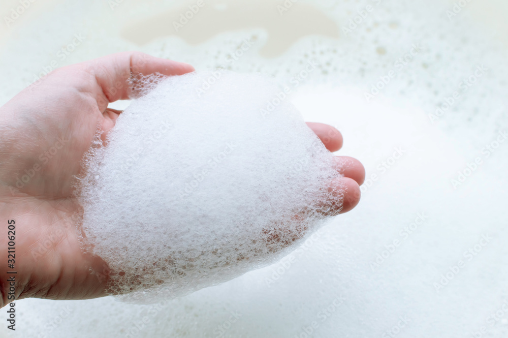 soap suds on a person's hand on a background of soap suds. The concept of cleanliness and hygiene. soap suds on a person's hand on a background of soap suds. The concept of cleanliness and hygiene.