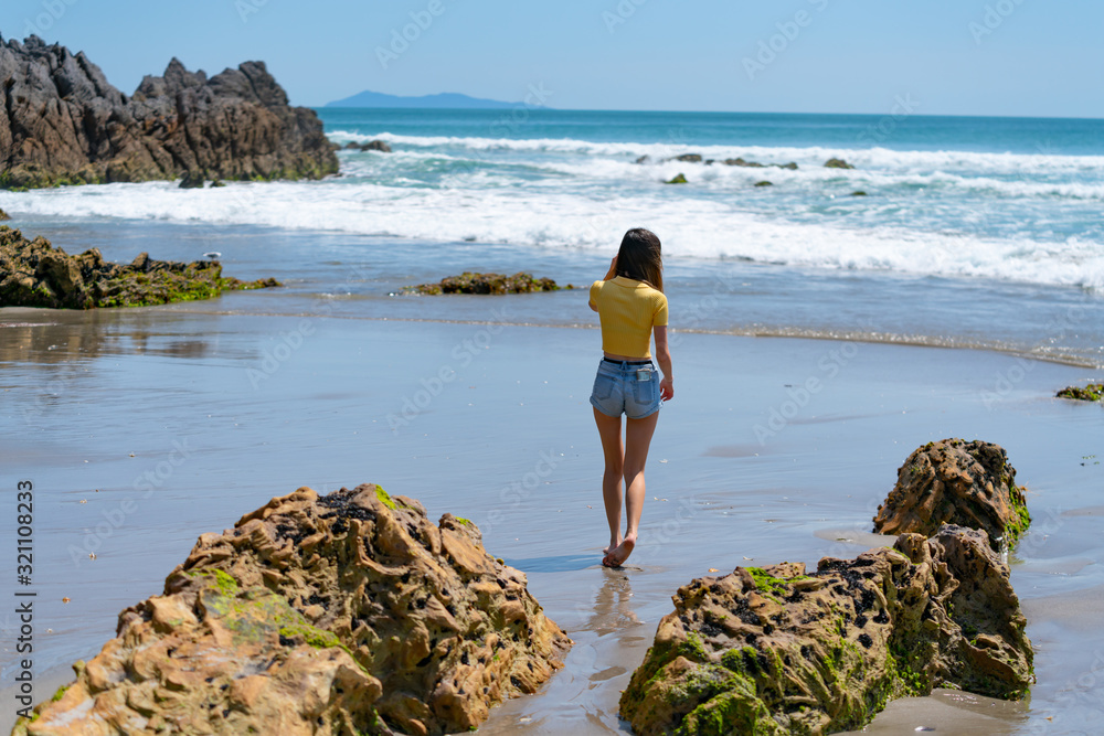 Young woman in bright yellow top walking near waters edge