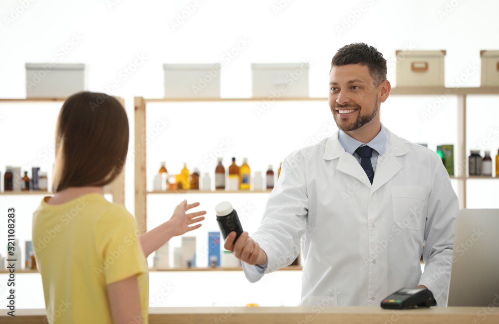 Pharmacist giving medicine to customer in drugstore Pharmacist giving medicine to customer in drugstore