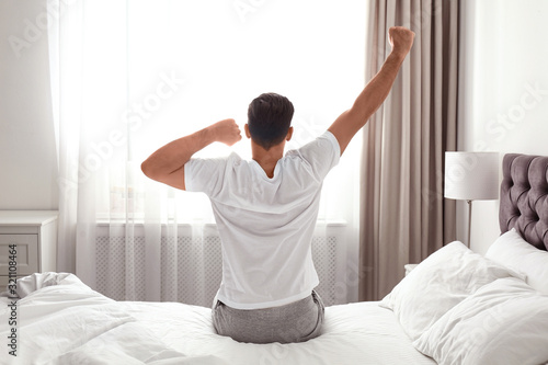 Man awakening on bed at home. Lazy morning