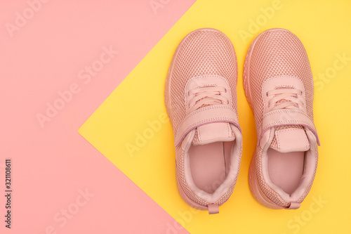 Pink sport shoes on colorful background. New sneakers on pink and yellow pastel background. Losing weight and sport concept. Top view, flat lay, copy space