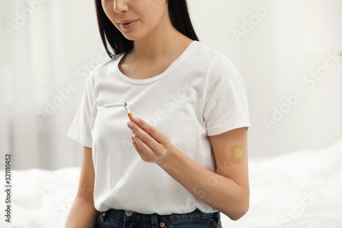 Young woman with nicotine patch and cigarette in bedroom, closeup photo