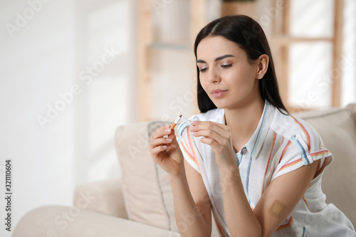 Fototapeta Naklejka Na Ścianę i Meble -  Young woman with nicotine patch and cigarette at home