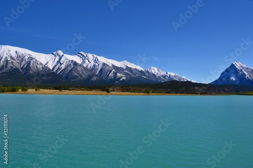 Beautiful blue Abraham Lake with high mountains covered with snow in the background. Sunny day, blue sky, Kootenay plains Ecological Reserve. Canada.