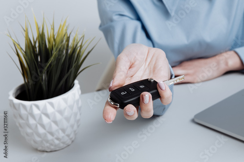 Yong pretty woman holding keys and giving it to the customer. Contract of buing a car photo