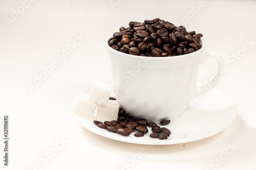 Coffee beans in a white glass with saucer on a white background