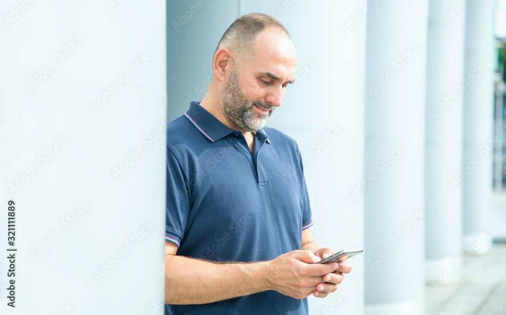 Middle aged man with a smartphone in his hands reads or writes a message. User of social networks. Middle aged man with a smartphone in his hands reads or writes a message. User of social networks.