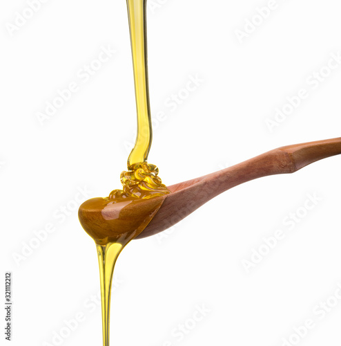 Falling and flowing honey on a wooden spoon isolated on white with clipping path photo