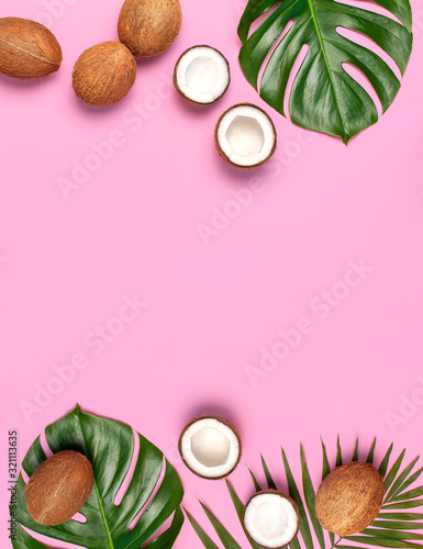 Summer Flat lay background. Frame of tropical leaves and fresh coconut on pink background top view copy space. Healthy cooking. Creative healthy food concept, half of coconut, nature