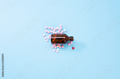 A photo of tablets poured from an amber glass bottle. Pharmaceutical medicine pills  pills from the heart on a blue background