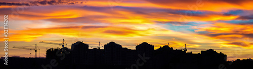 Panorama of colorful sunset sky over the silhouettes of houses
