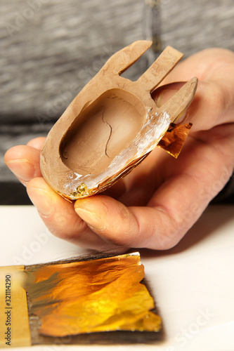 Artwork of gilding - covering an object with plate metal gold photo