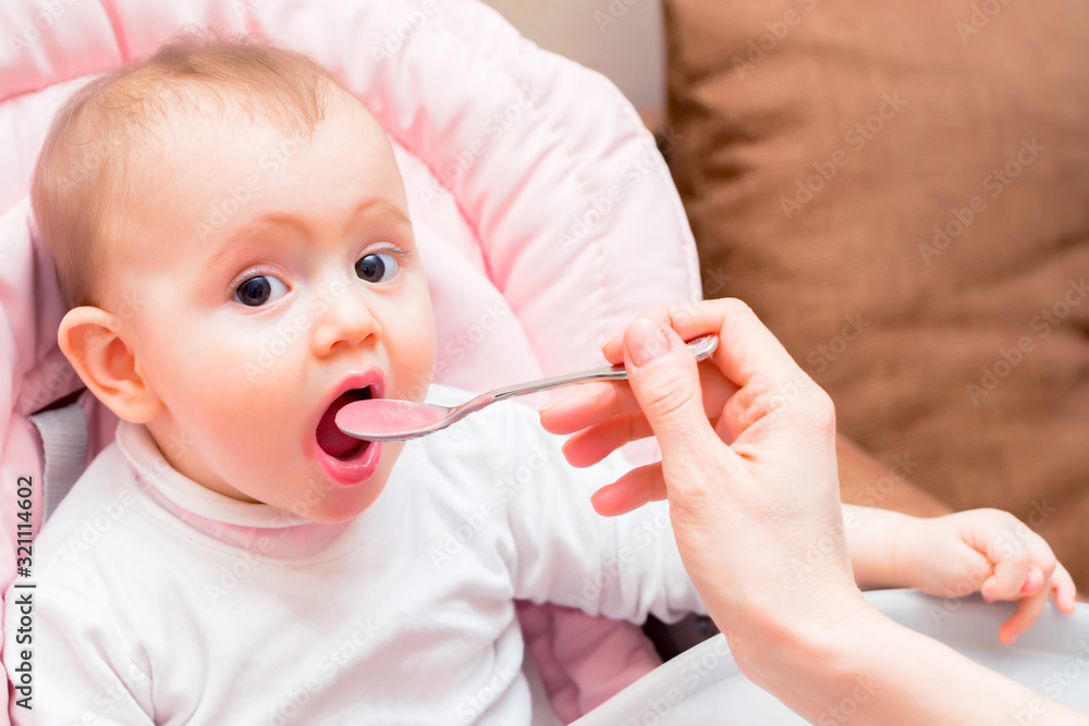 Feeding cute baby girl in pram with spoon Feeding cute baby girl in pram with spoon