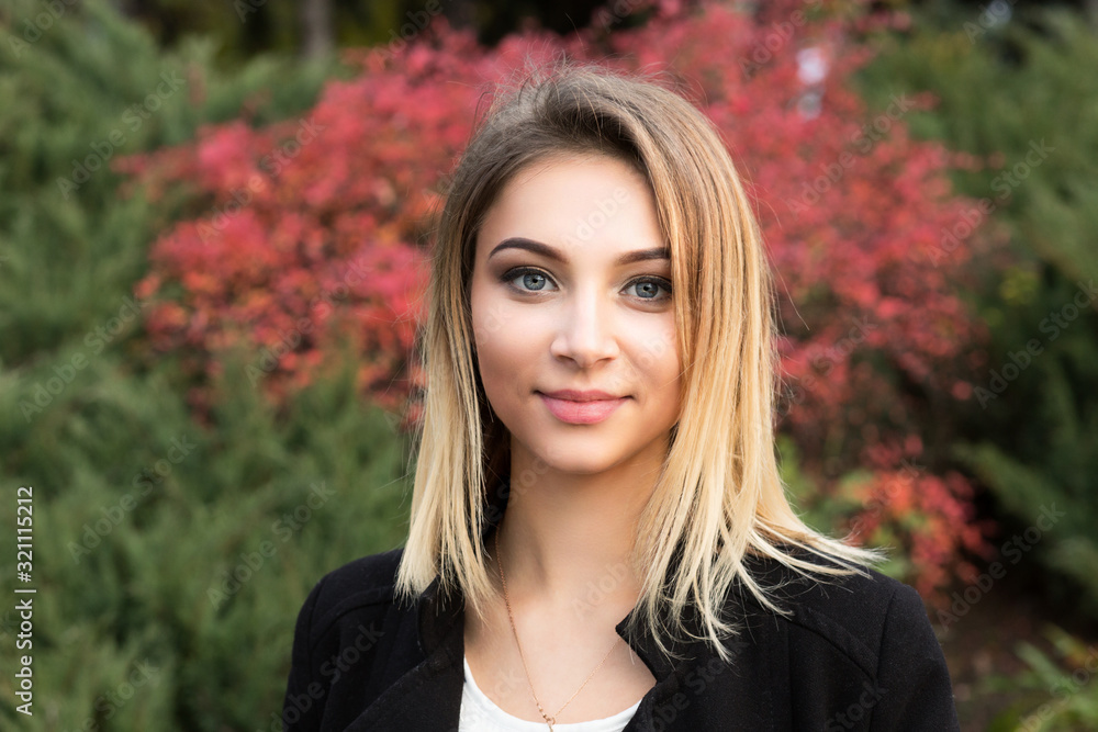 Naklejka premium Portrait of nice young woman against background of summer green park red green leaves beautiful woman