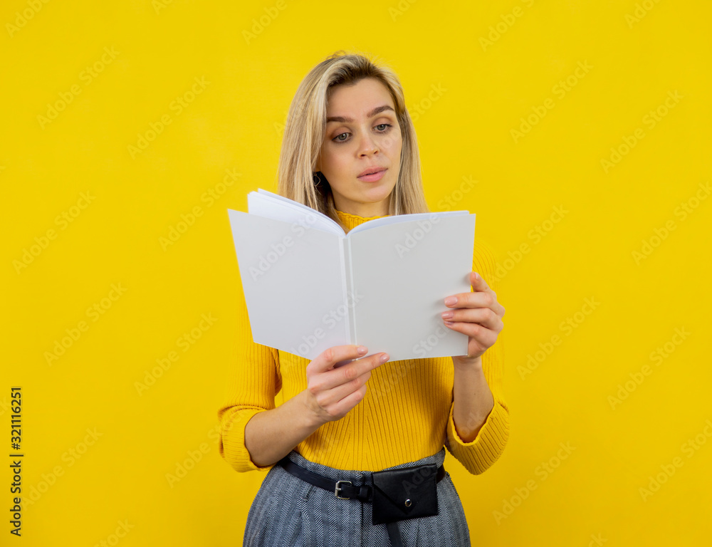 Young woman reading white magazine. Blank cover mockup. Studio shot on yellow background. Copy space Young woman reading white magazine. Blank cover mockup. Studio shot on yellow background. Copy space