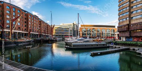 Panoramic view of International House near Tower Bridge House across St Katherine Docks in London with sailboats in the foreground
