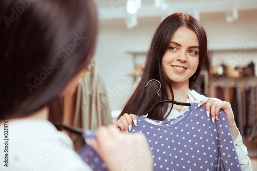 Attractive brunette woman enjoying trying dresses at clothing atore at the mall