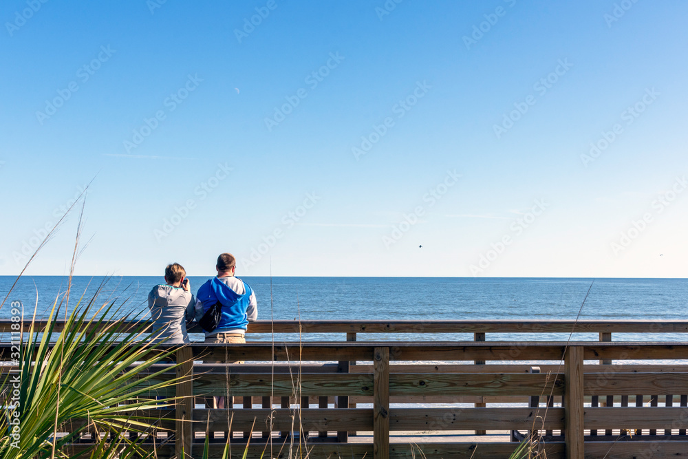 A couple enjoying the ocean view on Jekyll Island, Georgia, a popular slow travel tourism destination in the southeastern United States.