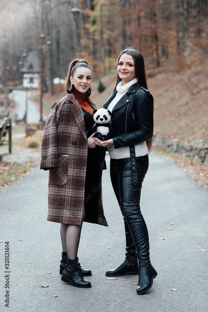 People, friends, teens and friendship concept - happy smiling pretty teenage girls hugging outdoors. Girlfriend friendship togetherness happiness smiling concept. Girl posing with a panda toy People, friends, teens and friendship concept - happy smiling pretty teenage girls hugging outdoors. Girlfriend friendship togetherness happiness smiling concept. Girl posing with a panda toy