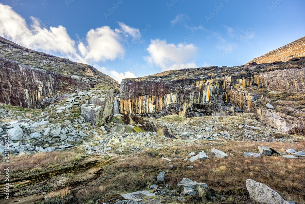 Naklejka premium Old stone quarry with waterfall in Mourne Mountains near Slieve Donard mountain. This mountain range is highest and most dramatic in Northern Ireland