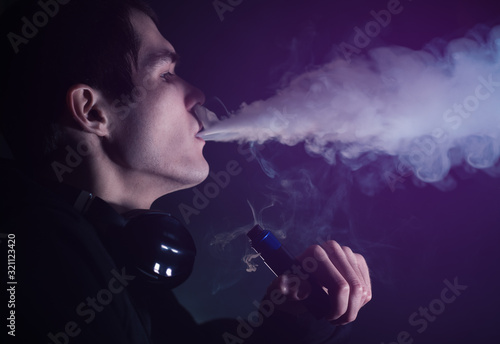 man in the clouds of steam from electronic cigarette closeup. vaping man