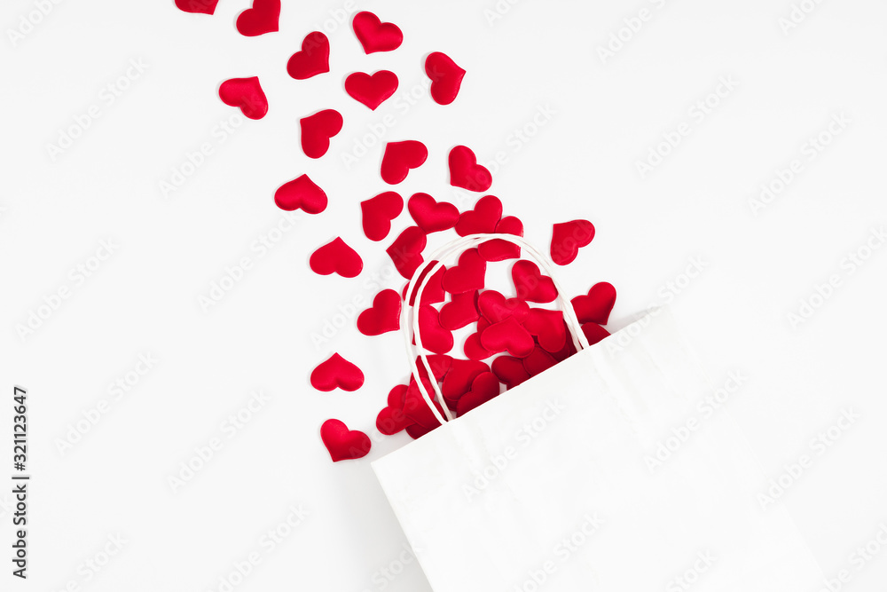 Elegant composition for Valentine's Day. Paper white gift bag, red hearts on white background. Valentine day, 8th march, Mother day background. Love concept. Flat lay, top view, copy space