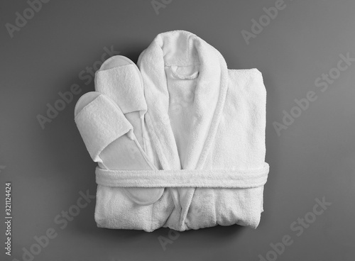 Clean folded bathrobe and slippers on grey background, top view photo