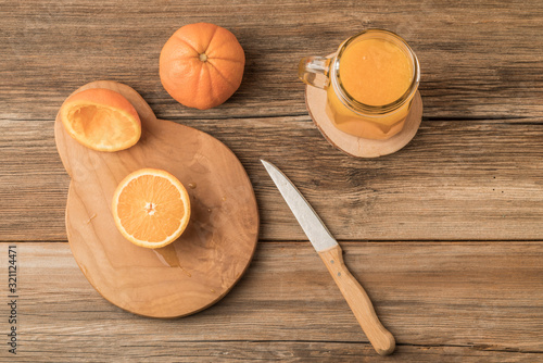 glass of fresh orange juice and oranges on cutting board