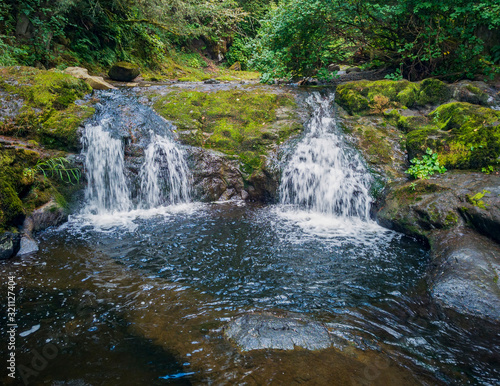 Fototapeta Naklejka Na Ścianę i Meble -  Remarkable Lower Little Mashel Falls cascading into a moss covered rocky surface leading to a small pool of water in the creek at the Charles Pack Forest during the summer in Pierce County Washington 