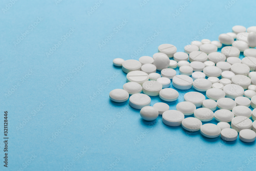 scattered white pills on a blue table. Layout for special offers such as advertising or other ideas. The concept of medicine, pharmacy and healthcare. Space for copy. flat lay for text or logo. scattered white pills on a blue table. Layout for special offers such as advertising or other ideas. The concept of medicine, pharmacy and healthcare. Space for copy. flat lay for text or logo.