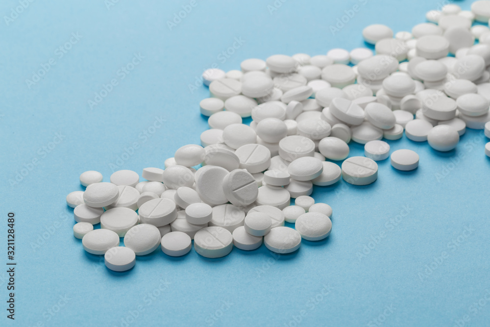 scattered white pills on a blue table. Layout for special offers such as advertising or other ideas. The concept of medicine, pharmacy and healthcare. Space for copy. flat lay for text or logo. scattered white pills on a blue table. Layout for special offers such as advertising or other ideas. The concept of medicine, pharmacy and healthcare. Space for copy. flat lay for text or logo.