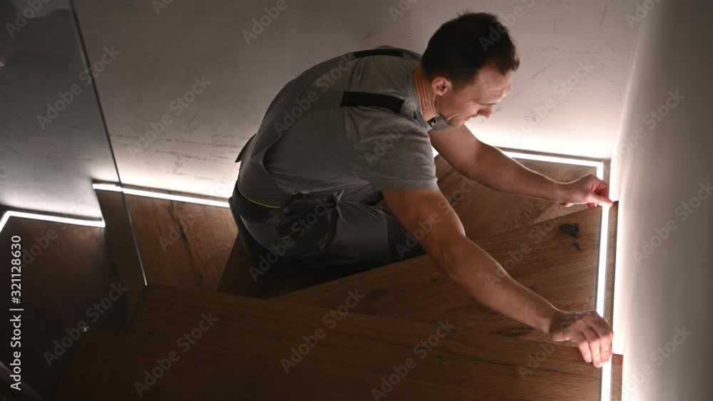 Worker Installing Home Stairs LED Illumination. Interior Lighting. Home Improvement Theme. Worker Installing Home Stairs LED Illumination. Interior Lighting. Home Improvement Theme.