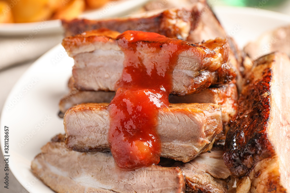 Delicious grilled ribs with sauce on table, closeup