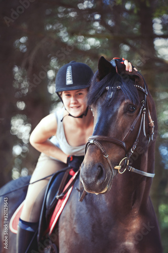 Black horse portrait with cheerful teenage girl equestrian