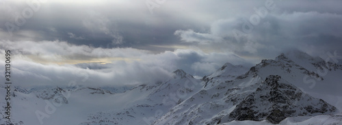 Mountain peaks in the snow and heavy clouds. View of the Main Caucasian Range in Russia