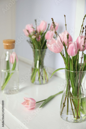 Beautiful bouquet with spring pink tulips on white window sill indoors