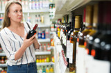 Alcoholic drinks in supermarket. Blurred woman on background.