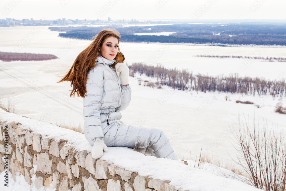 Young brunette woman in a silver ski suit posing on a hilltop Young brunette woman in a silver ski suit posing on a hilltop