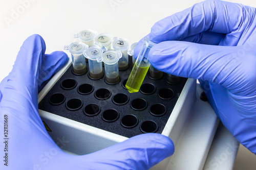 Coronavirus vaccine. Green substance in microtube is put in thermo shaker. DNA experiment in biochemical laboratory photo