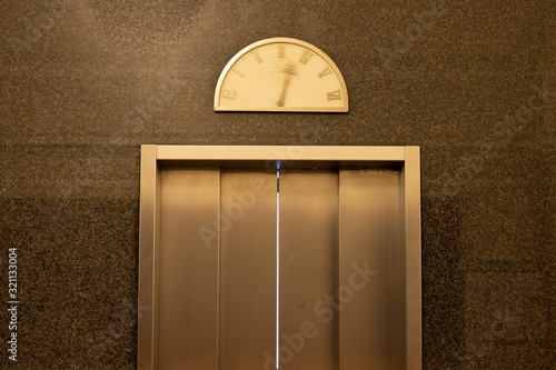 Detail of an elevator door with moving pointer on a vintage floor level display photo