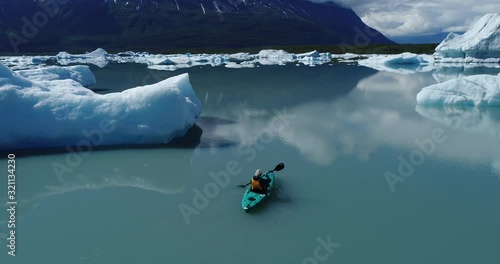 Drone footage of woman kayaking by icebergs in water, Alaska, USA