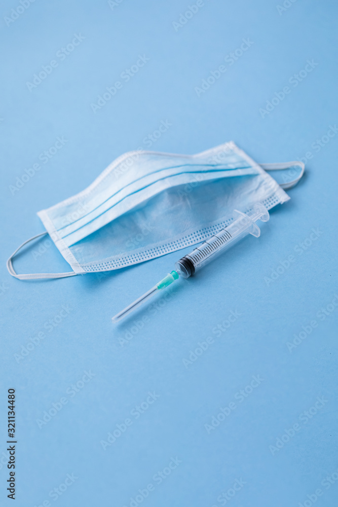 Protective surgical face mask with a syringe, medical cure concept, with a copy space Protective surgical face mask with a syringe, medical cure concept, with a copy space
