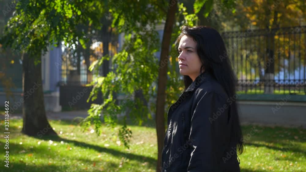 Serious Beautiful Girl Walking In The City Park And Thinking. Autumn Sunny Day In City Park. Morning Sunlight. Slow motion 60 fps Serious Beautiful Girl Walking In The City Park And Thinking. Autumn Sunny Day In City Park. Morning Sunlight. Slow motion 60 fps