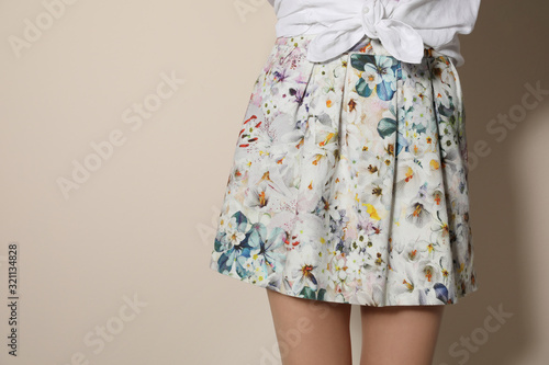Photo Young woman wearing floral print skirt on beige background, closeup