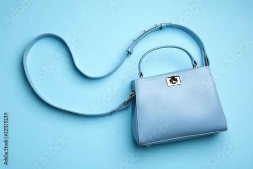 Stylish woman's bag on light blue background, top view photo