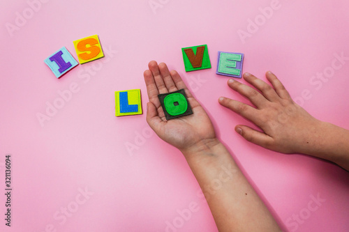 The word IS LOVE. Hands of the child hold letters. Alphabet. Learn letters with a child. ABC