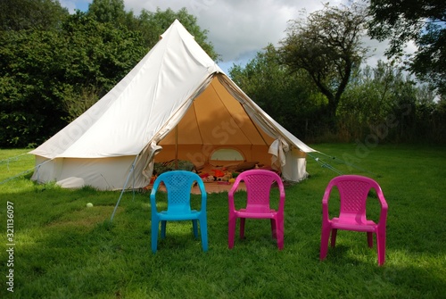 Bell tent in a field with 3 plastic chairs