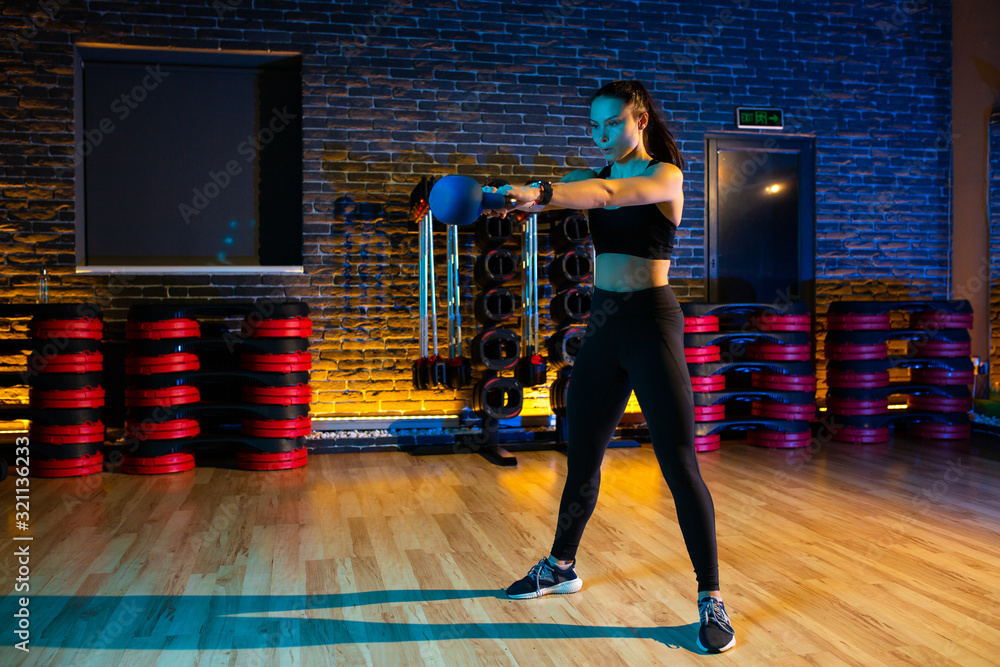 Obraz premium Fit young woman workout in the gym with kettlebell.