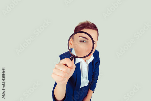 Bilde på lerret Skeptical woman looking through magnifying glass isolated yellow wall background