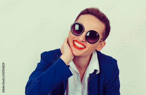 Smiling happy fashion woman wearing sunglasses portrait in studio isolated light green background